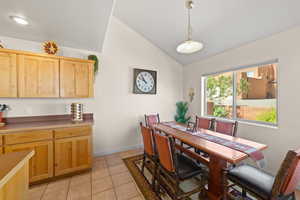 Dining area with vaulted ceiling and light tile patterned flooring