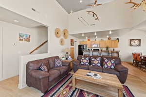 Living room featuring ceiling fan, light wood-style floors, and a high ceiling