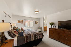 Carpeted bedroom featuring ensuite bathroom and baseboards