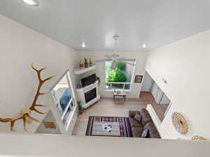 Living room with a glass covered fireplace, wood finished floors, and a ceiling fan