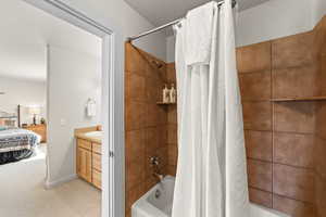 Bathroom featuring shower / bath combo with shower curtain, ensuite bath, light carpet, and vanity