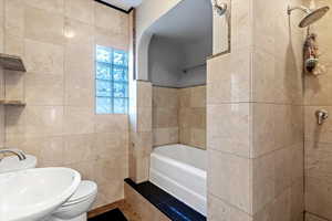 Full bath with tile walls, a bath, and a shower