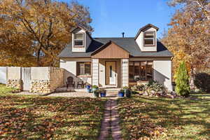 View of front facade with a shingled roof and a front lawn