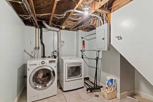 Washroom featuring light tile patterned flooring, separate washer and dryer, and electric panel