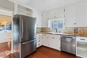 Kitchen featuring stainless steel appliances, white cabinets, open shelves, and dark wood-type flooring