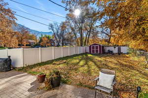 Fenced backyard featuring a storage unit, a mountain view, and a patio