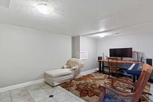 Office area with a textured ceiling and light tile patterned floors