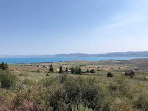 View of mountain backdrop featuring a nearby body of water and rural landscape