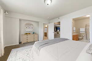 Bedroom featuring ensuite bath, carpet flooring, and a walk in closet