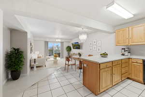 Kitchen with light countertops, open floor plan, a peninsula, light tile patterned floors, and a chandelier