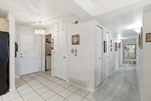 Corridor with light tile patterned flooring and a chandelier