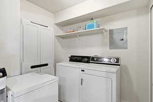 Laundry room with electric panel and washer and clothes dryer