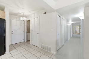 Hall featuring suspended lighting and light tile patterned floors