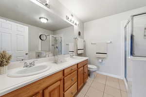 Full bath featuring double vanity, a shower stall, and light tile patterned flooring