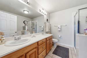 Full bath featuring double vanity, light tile patterned floors, and a stall shower
