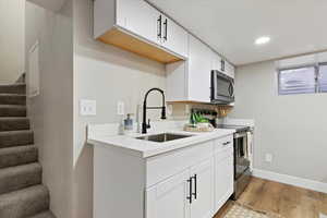 Kitchen with stainless steel appliances, light wood-style flooring, white cabinets, and recessed lighting