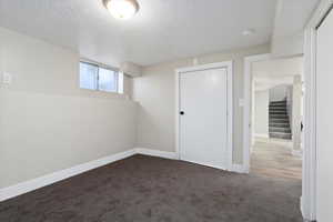 Below grade area featuring carpet flooring, a textured ceiling, and stairway