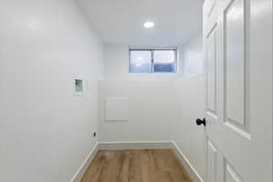 Laundry area with light wood-style floors and hookup for a washing machine