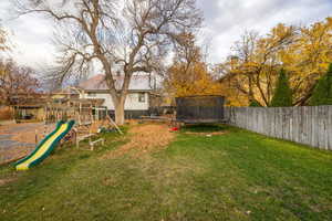 Fenced backyard with a trampoline and a playground
