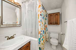 Bathroom with light tile patterned floors, a textured ceiling, vanity, and a shower with curtain