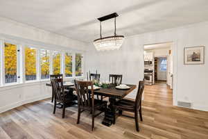 Dining area with light wood-style flooring, crown molding, and a chandelier