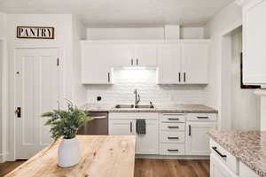 Kitchen with a textured ceiling, wooden counters, dark wood-style flooring, and white cabinets