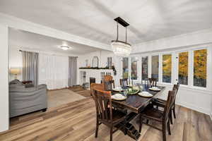 Dining area with a brick fireplace, wood finished floors, a chandelier, and crown molding
