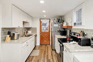 Kitchen featuring stainless steel appliances, white cabinets, tasteful backsplash, light countertops, and open shelves