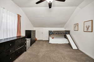 Unfurnished bedroom featuring a textured ceiling, light carpet, vaulted ceiling, and a ceiling fan
