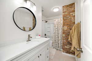 Full bathroom with vanity, shower / bath combo, and a textured ceiling