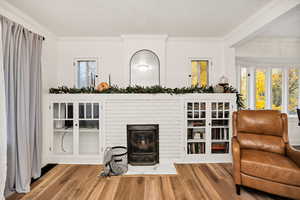 Living room featuring crown molding, wood finished floors, healthy amount of natural light, and a fireplace