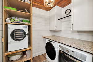 Washroom with washer and dryer, dark wood-style flooring, wooden walls, and wood ceiling