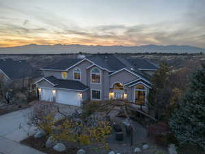 Traditional-style house with roof with shingles, stucco siding, a chimney, driveway, and a mountain view