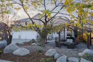 View of front of home with a garage, a patio area, stone siding, driveway, and outdoor lounge area