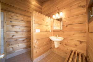 Bathroom featuring wood walls and tile patterned floors