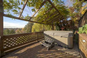 Wooden terrace with a hot tub, a mountain view, and a patio