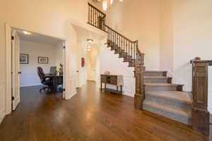 Entrance foyer with dark wood flooring, stairway, and a high ceiling
