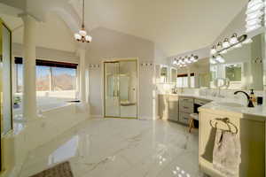 Full bathroom featuring a shower stall, light marble finish flooring, a garden tub, double vanity, and high vaulted ceiling