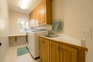 Laundry area with cabinet space, washing machine and dryer, and light flooring