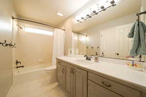 Full bath with shower / bath combo, vanity, and light marble finish flooring