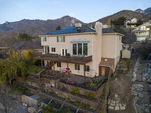 Rear view of property with stucco siding, a garden, solar panels, a chimney, and a patio