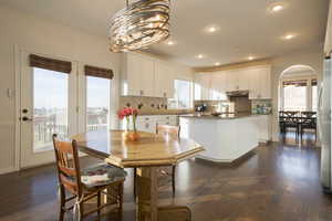 Dining room featuring dark wood floors, plenty of natural light, a chandelier, and recessed lighting