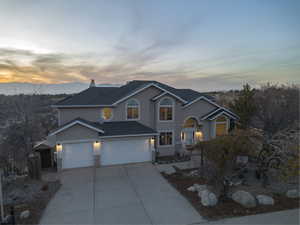 Traditional-style home featuring stucco siding, driveway, roof with shingles, and a chimney