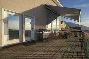 Wooden deck with a mountain view, a grill, and outdoor dining space
