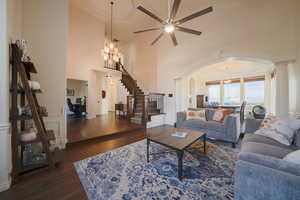 Living room with stairs, dark wood floors, a decorative wall, arched walkways, and a chandelier