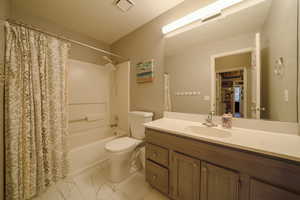 Full bathroom featuring vanity, shower / tub combo with curtain, and light marble finish floors