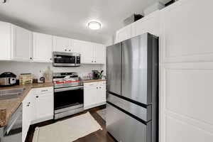 Kitchen featuring stainless steel appliances, white cabinets, and dark wood finished floors