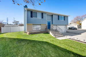 Split foyer home featuring brick siding, a chimney, concrete driveway, and a garage