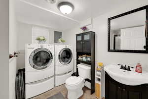 Full bathroom featuring a textured ceiling, vanity, washing machine and clothes dryer, electric panel, and a shower with door