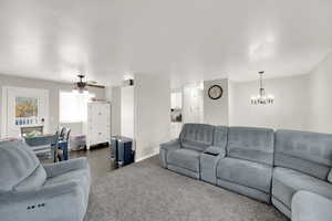 Living room featuring a ceiling fan and dark colored carpet